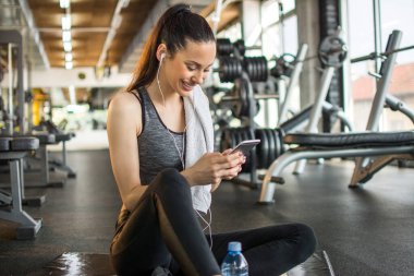 Spor antrenmanından sonra telefonu kullanan çekici, fit bir kadın..
