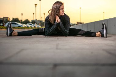 Çekici, ciddi, genç bir kadın kaldırımda ikiye ayrılıyor. Spor yapan kadın dışarıda egzersiz yapıyor.