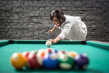 Gözlüklü ve takım elbiseli, bilardo oynayan Afro-Amerikalı genç bir iş kadını. Snooker oyuncusu.