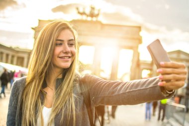 Berlin, Almanya 'daki Brandenburg Kapısı önünde selfie çeken güzel sarışın kadın..