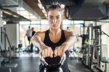 Çekici sporcu kız spor salonunda kettlebell ile egzersiz yapıyor..