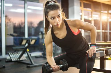 Spor salonunda ağırlık kaldıran genç bir kız..