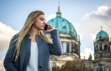 Berliner 'in önünde cep telefonuyla konuşan iş kadını Dom, Berlin, Almanya.