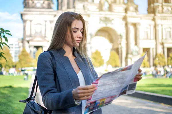 Beautiful young woman searching for city sights and attractions on map.
