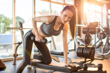 Spor salonunda halteri kaldıran genç bir kadın. Sabah egzersizi.