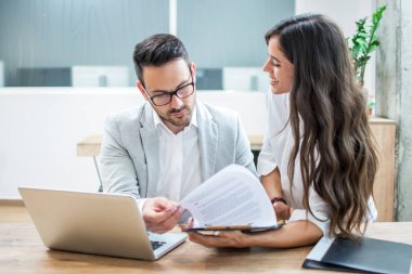 İş adamı ve kadın masa başında oturmuş raporlar ve ofis finansmanı hakkında konuşuyorlar.