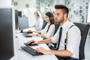 Ofiste bilgisayarla çalışan çekici genç adam.