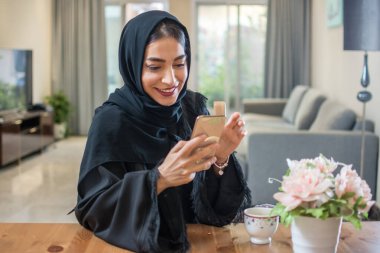 Evde cep telefonu kullanan gülümseyen Arap kızın portresi.