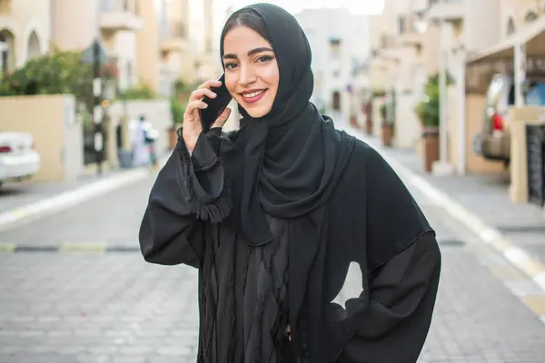 Portrait of beautiful middle east young woman talking on mobile phone outdoors.