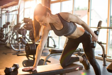 Zayıf formda sporcu kız spor salonunda ağırlık çalışıyor..