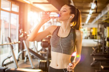 Spor salonunda spor yaparken su içen formda, zayıf bir sporcu kadın..