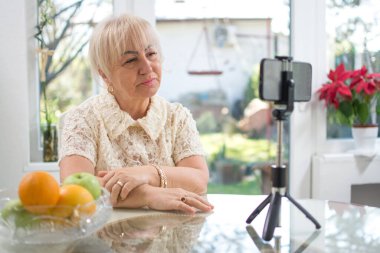 Evde akıllı telefondan video görüşmesi yapan üzgün, olgun bir kadın. İnternetten ailesiyle video görüşmesi yaparken ağlayan orta yaşlı bir kadın..