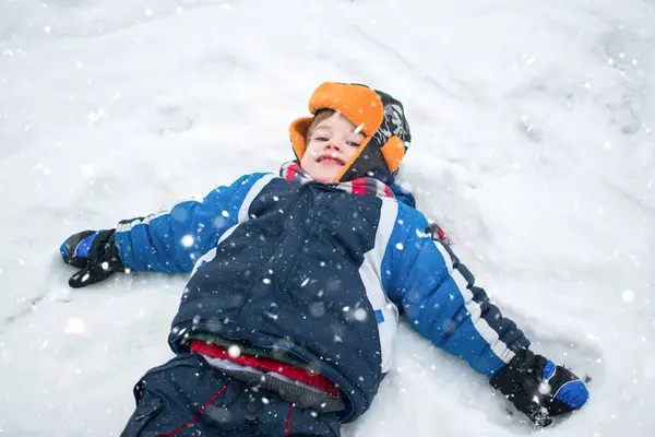 Kış Giysileri Içinde Kar Üzerinde Uzanmış Küçük Bir Çocuk Bir — Stok fotoğraf