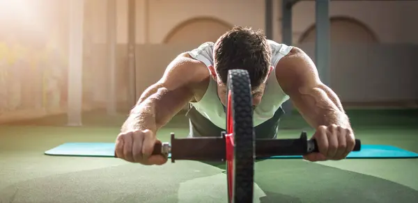 Kaslı Adamın Spor Salonunda Abdominal Silindirle Egzersiz Yaptığı Panoramik Manzara — Stok fotoğraf