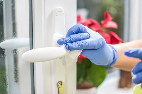 Womans hands in medical gloves wiping the door handle. World pandemic Coronavirus prevention.