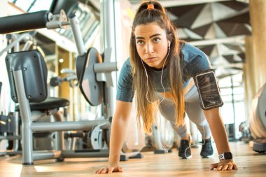 Spor kıyafetleri içinde güzel bir fitness kızı spor salonunda tahta egzersizi yapıyor..