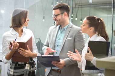 Bir grup genç iş adamı ofis lobisinde belgeleri tartışıyor..