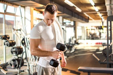 Genç yakışıklı adam spor salonunda ağırlık kaldırıyor.