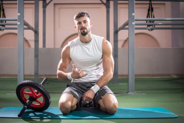 Spor salonunda jimnastik yaptıktan sonra dinlenen yakışıklı adam..