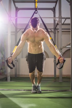 Spor salonunda trx fitness kayışlı yakışıklı kaslı adam eğitimi..