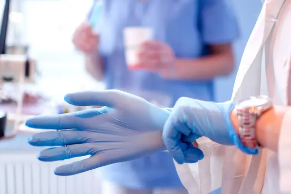 Zbliżenie Kobiety Lekarze Ręce Zakładanie Niebieski Sterylizowane Rękawice Chirurgiczne Klinice — Zdjęcie stockowe