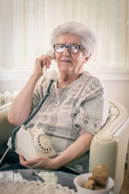 Ev telefonunda konuşan yaşlı bir kadın..