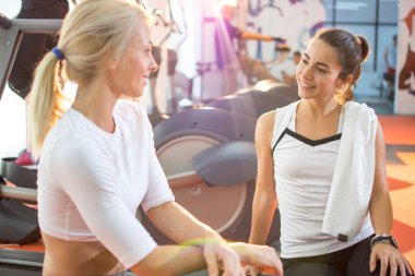 Sportif kız arkadaşlar spor salonunda sıkı çalıştıktan sonra konuşuyorlar..