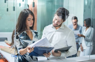 İş kadını ve işadamı ofiste görüşüyorlar. Cam manzaralı.