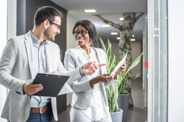 Ofiste duran ve belgeleri tartışan iki iş adamı..