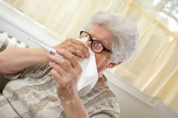 Starší Žena Kontroluje Tělesnou Teplotu Teploměrem Otírá Nos Papírem — Stock fotografie