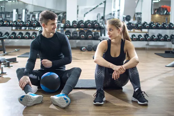 Sportif çift spor salonunda egzersiz arasında konuşuyor.