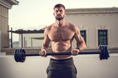 Mükemmel karın kasları, omuzları, pazıları, trisepsleri ve halterli göğüs egzersizleri olan kaslı bir adam..