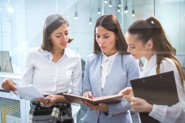 Parlak ofiste üç iş kadınının konuşması. İş, evraklar, belgeler, toplantı konsepti.