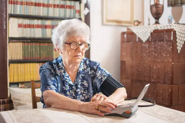 Dijital Tansiyon Monitörü Kullanarak Kan Basıncını Ölçen Yaşlı Bir Kadın — Stok fotoğraf