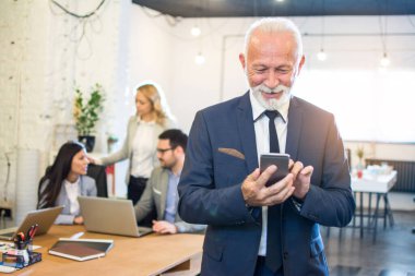 Seçkin takım elbiseli üst düzey işadamının resmi. Ofiste telefon kullanıyor..