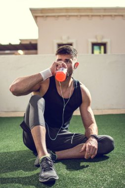 Spor eğitiminden sonra enerji içeceği içen yakışıklı bir adam.