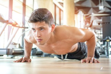 Spor salonunda şınav çeken genç bir adam.
