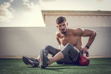 Kaslı sakallı adam dışarıda ağırlık çalışıyor.