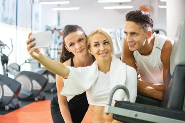 Spor salonunda akıllı telefonla selfie çeken bir grup mutlu genç..
