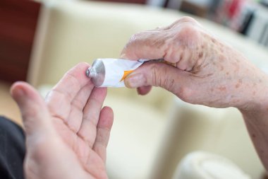 Evde krem sürerken buruşuk elleri olan yaşlı kadınların yakın plan fotoğraflarını çek..