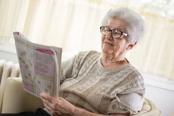 Glad Äldre Kvinna Lösa Ett Korsord Hemma — Stockfoto