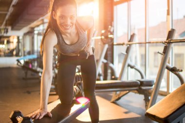 Güzel formda genç bir kadın spor salonunda ağırlık kaldırıyor.