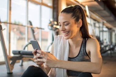 Spor salonundaki antrenmandan sonra telefonu kullanan güzel bir kadın..