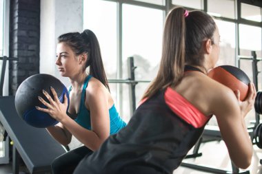 Sporcu kadınlar spor salonunda spor toplarıyla egzersiz yapıyorlar.