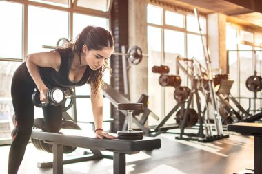 Sportif kız spor salonunda ağırlık kaldırıyor.