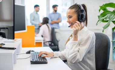 Ofiste bilgisayarla çalışan kulaklıklı çağrı merkezinin güzel kadın danışmanı..