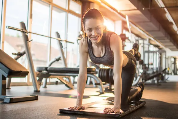 Genç, formda bir kadın spor salonunda bacak egzersizi yapıyor.