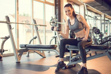 Sporcu kadın spor salonunda ağırlık kaldırıyor..