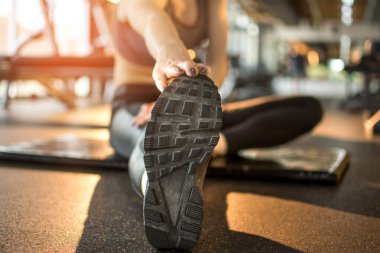 Kadın elinin oturma pozisyonundan ayak parmaklarına dokunuşunu yakından görmek, spor salonunda esneklik egzersizi gibi.