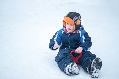 Kış günü açık havada uçan daire kızakları olan sevimli küçük bir çocuk. Tepeden kayan heyecanlı çocuk